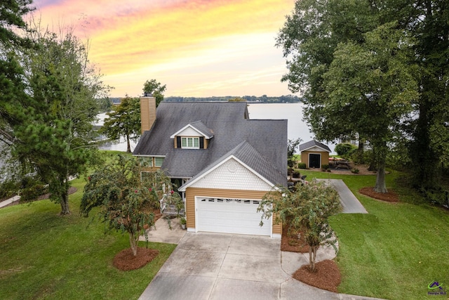 view of front of home featuring a water view, a lawn, and a garage