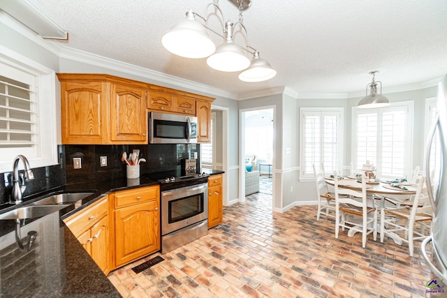 kitchen featuring backsplash, stainless steel appliances, sink, pendant lighting, and a textured ceiling