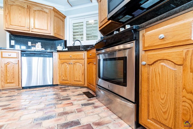 kitchen with dark stone countertops, sink, stainless steel appliances, backsplash, and ornamental molding