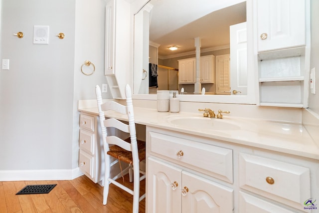 bathroom with wood-type flooring, vanity, and ornamental molding