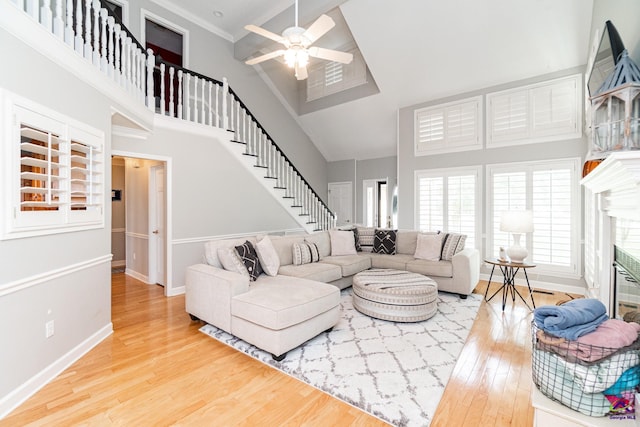 living room with crown molding, a high ceiling, hardwood / wood-style floors, and ceiling fan