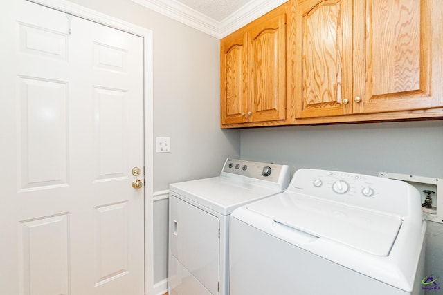 clothes washing area with washer and clothes dryer, cabinets, and ornamental molding