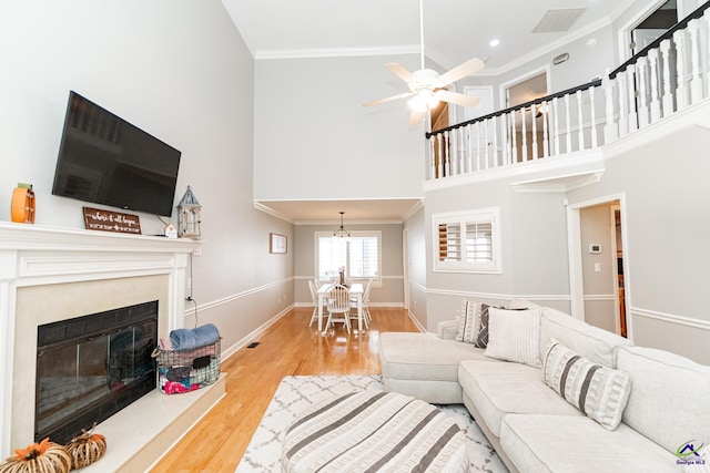 living room with crown molding, a high ceiling, hardwood / wood-style floors, and ceiling fan