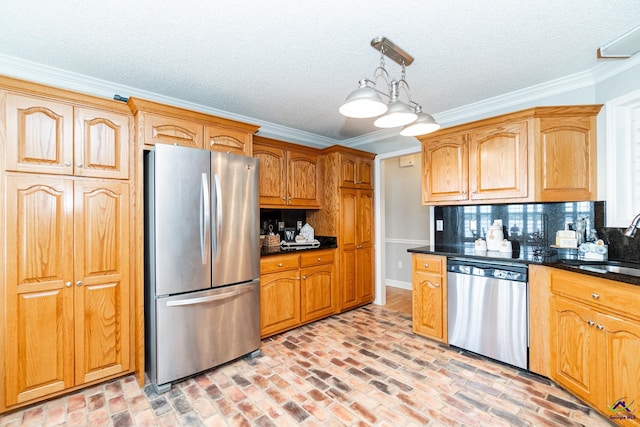 kitchen with hanging light fixtures, ornamental molding, sink, stainless steel appliances, and decorative backsplash