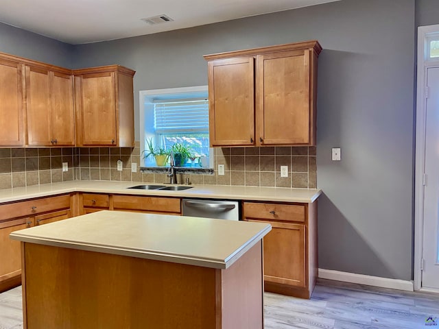 kitchen with dishwasher, light hardwood / wood-style floors, tasteful backsplash, and a kitchen island