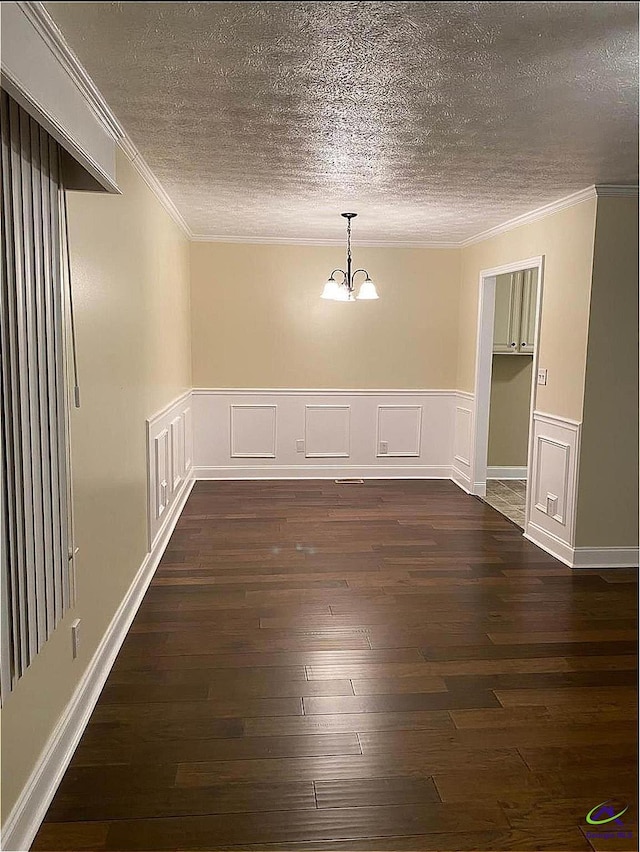 spare room with an inviting chandelier, crown molding, dark hardwood / wood-style flooring, and a textured ceiling