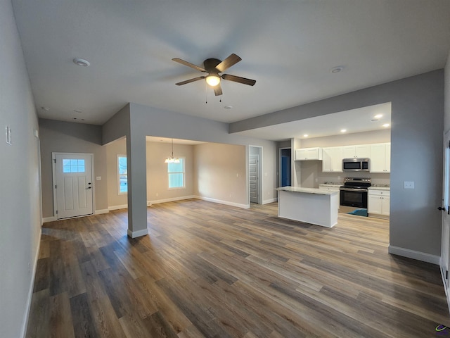 kitchen with white cabinetry, ceiling fan with notable chandelier, dark hardwood / wood-style flooring, and appliances with stainless steel finishes