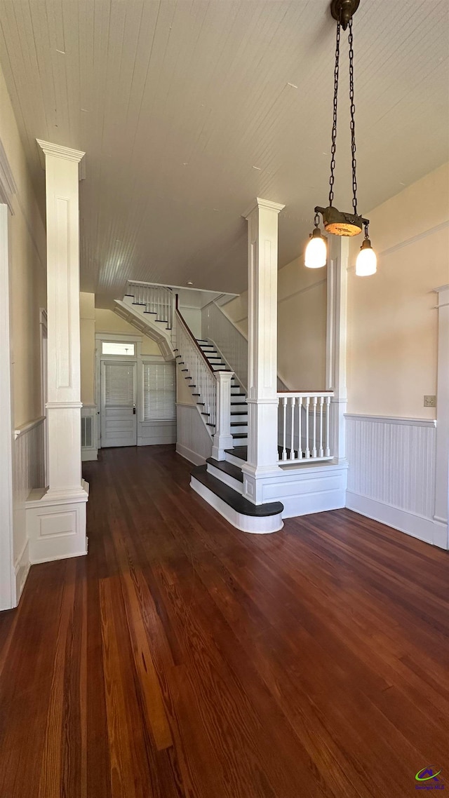 unfurnished living room featuring dark wood-type flooring and ornate columns