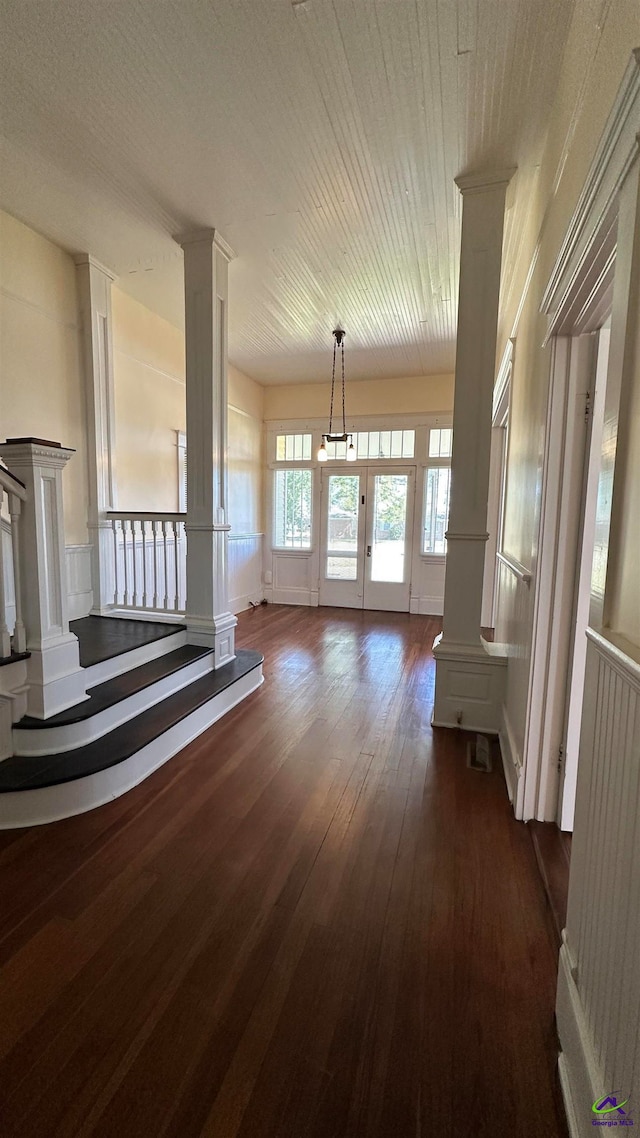 unfurnished living room with ornate columns and dark hardwood / wood-style floors