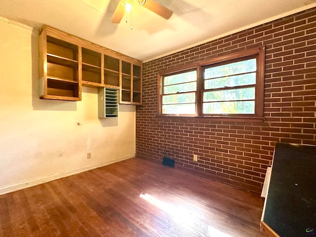 spare room featuring brick wall, dark wood-type flooring, and ceiling fan