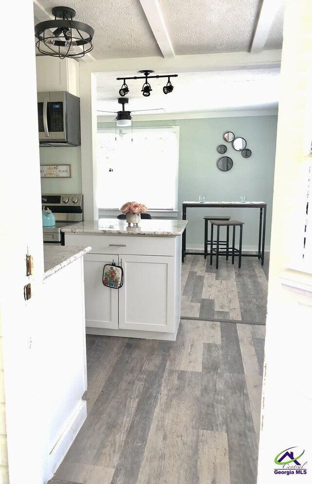5415 Beulah Ave, Eastman, GA 31023 - kitchen featuring appliances with stainless steel finishes, white cabinetry, wood finished floors, light stone countertops, and a textured ceiling