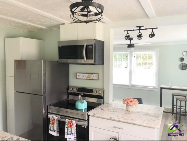 kitchen featuring hardwood / wood-style flooring, beam ceiling, light stone countertops, white cabinetry, and appliances with stainless steel finishes