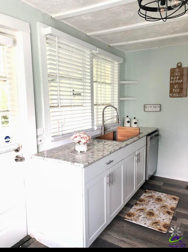 kitchen with white cabinets, light stone countertops, stainless steel dishwasher, dark wood-type flooring, and sink