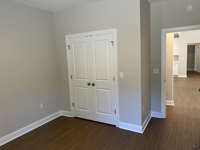 unfurnished bedroom with dark hardwood / wood-style flooring and a closet