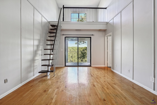 interior space with a towering ceiling and light hardwood / wood-style flooring