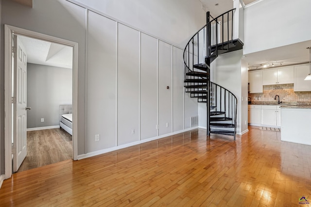 stairway with hardwood / wood-style flooring, a towering ceiling, and sink