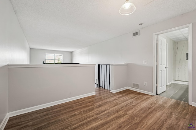 spare room with a textured ceiling and wood-type flooring