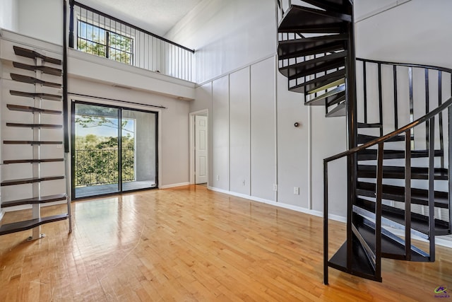 stairs featuring hardwood / wood-style floors, a textured ceiling, and a towering ceiling