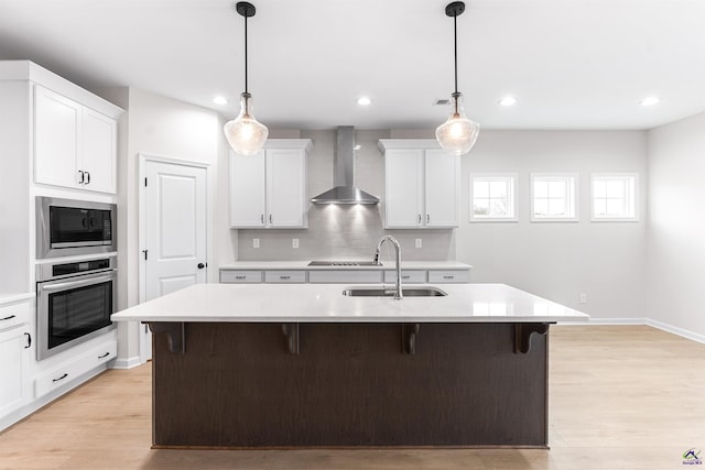 kitchen with wall chimney exhaust hood, a breakfast bar area, oven, built in microwave, and a sink