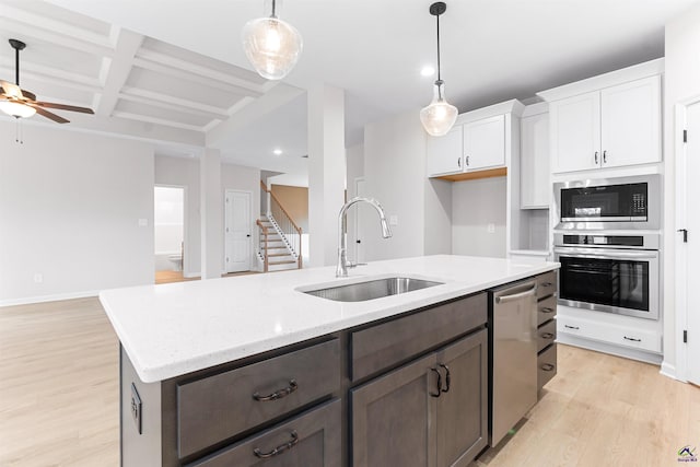 kitchen with coffered ceiling, a sink, white cabinetry, appliances with stainless steel finishes, and light wood finished floors