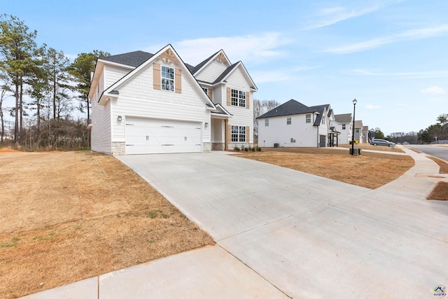 traditional-style house featuring a front yard, stone siding, an attached garage, and concrete driveway