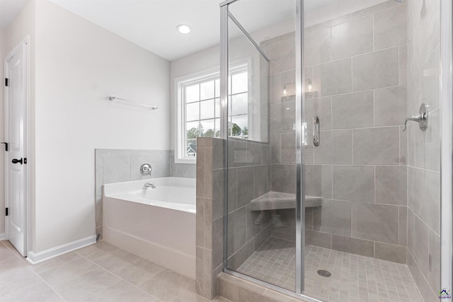 full bathroom featuring a stall shower, a garden tub, baseboards, and tile patterned floors