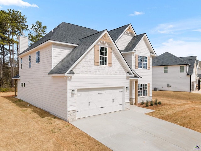 view of front facade featuring driveway, stone siding, roof with shingles, and a front yard