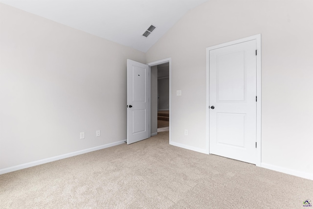 unfurnished bedroom with vaulted ceiling, baseboards, visible vents, and light colored carpet