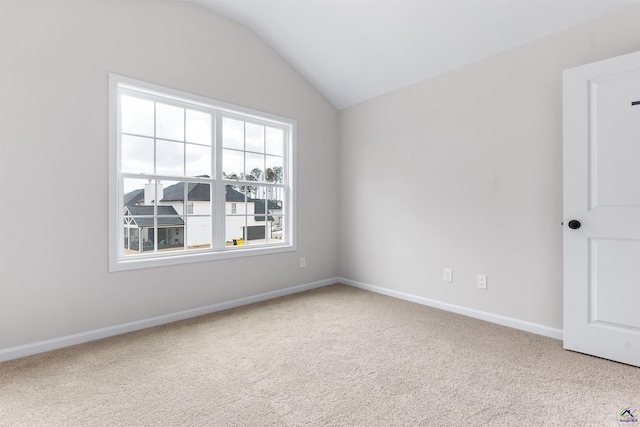 spare room with carpet floors, vaulted ceiling, and baseboards