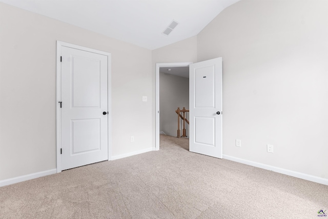 unfurnished bedroom featuring carpet, visible vents, vaulted ceiling, and baseboards