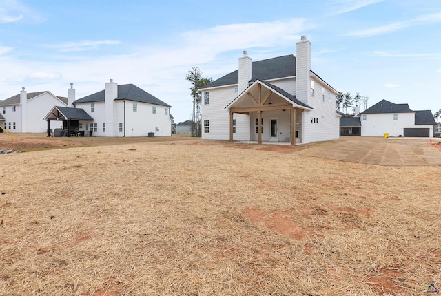 back of house featuring a chimney and a yard