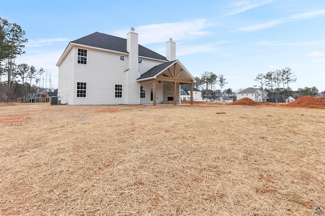 rear view of house featuring central AC unit, a chimney, and a shingled roof