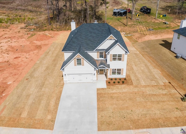 view of front facade with a garage, concrete driveway, and a chimney