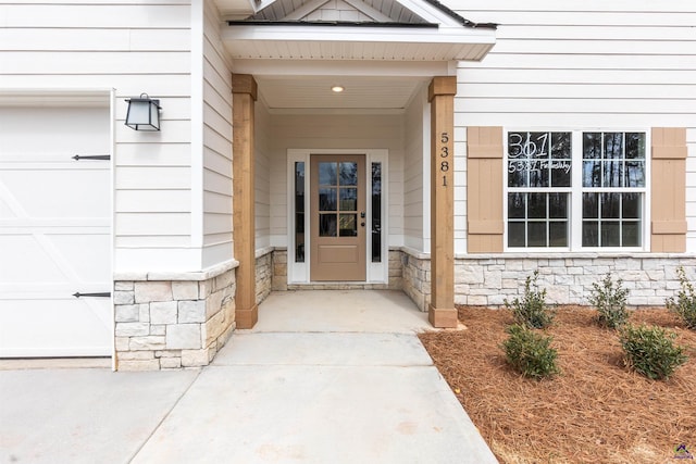 property entrance featuring a garage and stone siding