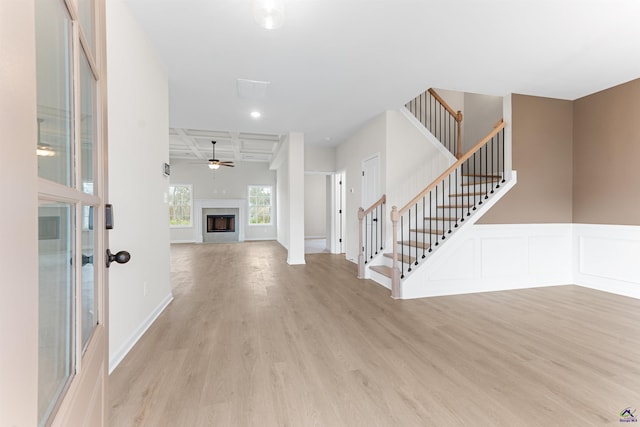 entrance foyer featuring light wood-style floors, a fireplace, stairway, and coffered ceiling