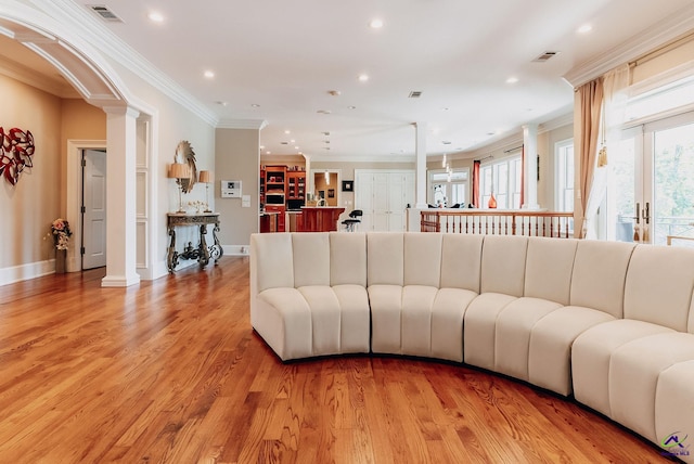 living room featuring ornate columns, crown molding, and light wood-type flooring