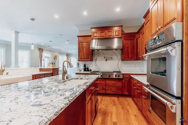 kitchen featuring ornamental molding, appliances with stainless steel finishes, decorative light fixtures, and light hardwood / wood-style floors