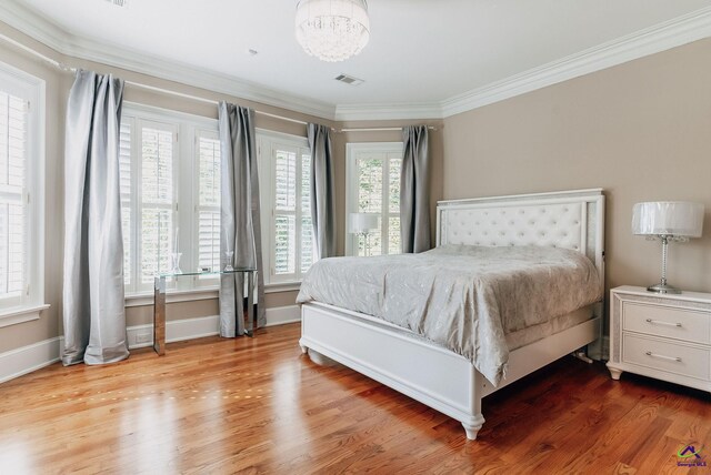 bedroom featuring ornamental molding, an inviting chandelier, and hardwood / wood-style floors