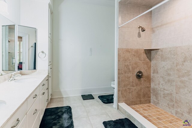 bathroom featuring vanity, tile patterned flooring, toilet, and tiled shower