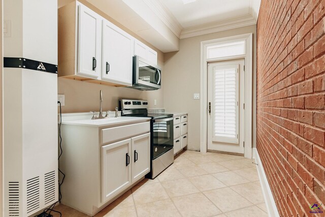 kitchen featuring brick wall, ornamental molding, white cabinetry, and stainless steel appliances