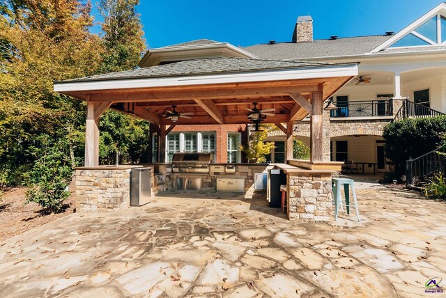 view of patio / terrace featuring a gazebo, exterior kitchen, ceiling fan, a bar, and a grill