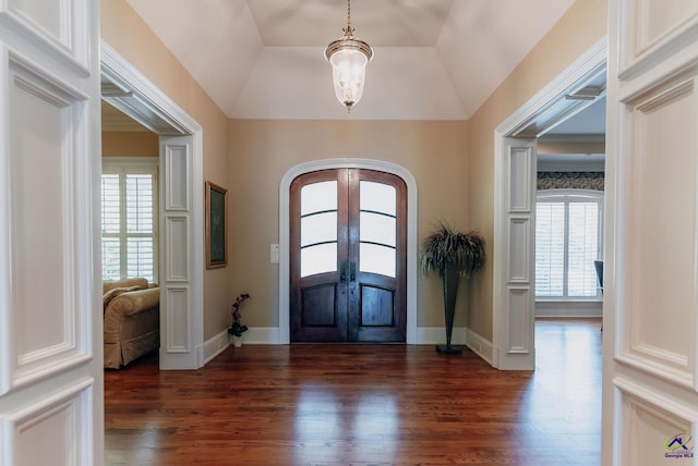 foyer with dark wood-type flooring, a tray ceiling, french doors, and vaulted ceiling