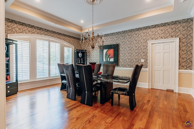 dining area featuring ornamental molding, hardwood / wood-style floors, an inviting chandelier, and a raised ceiling