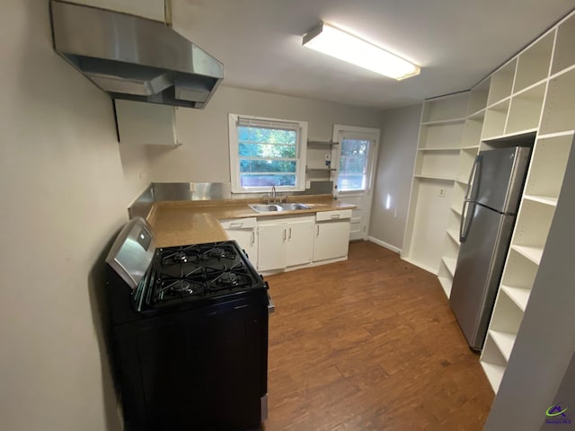 kitchen featuring black range with gas stovetop, sink, white cabinets, stainless steel refrigerator, and exhaust hood