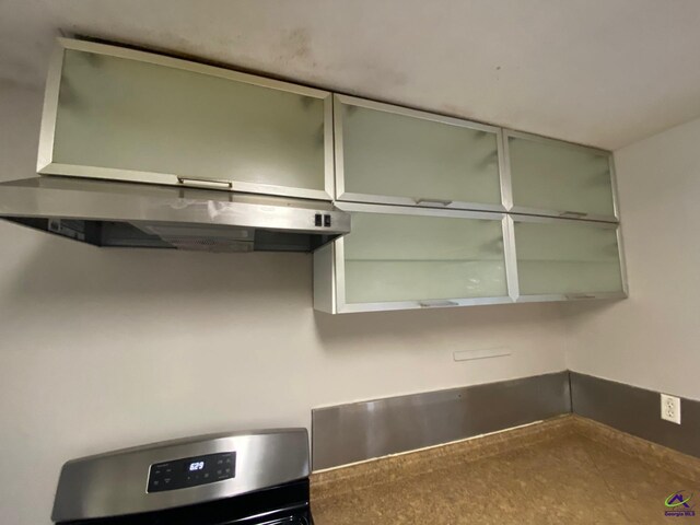 kitchen featuring range hood, stainless steel range oven, and green cabinets