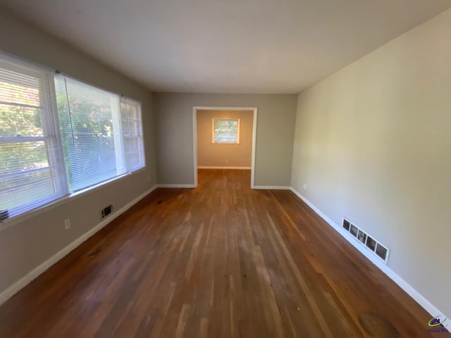 empty room with dark wood-type flooring and plenty of natural light