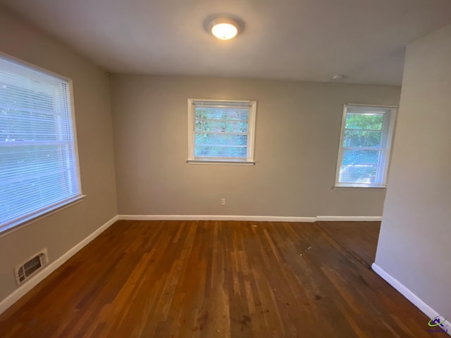 empty room featuring dark wood-type flooring and a healthy amount of sunlight