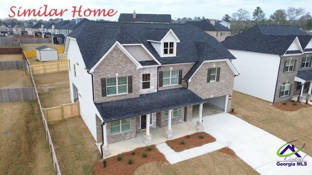 traditional home with fence, stone siding, a garage, a porch, and driveway