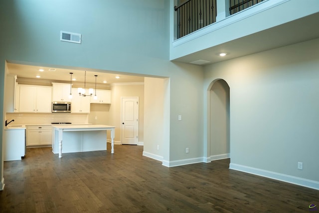 interior space with baseboards, arched walkways, wood finished floors, and visible vents