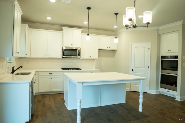 kitchen featuring white cabinets, appliances with stainless steel finishes, a sink, decorative backsplash, and a kitchen island